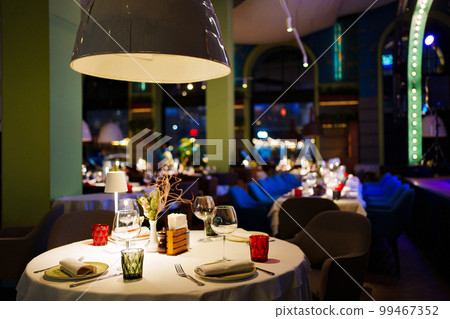 a table with a white tablecloth, glasses, crockery and decor in dark restaurant a table with a white tablecloth, glasses, crockery and decor in dark restaurant 99467352