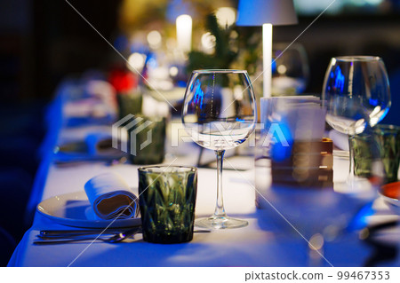 a table with a white tablecloth, glasses, crockery and decor in dark restaurant a table with a white tablecloth, glasses, crockery and decor in dark restaurant 99467353