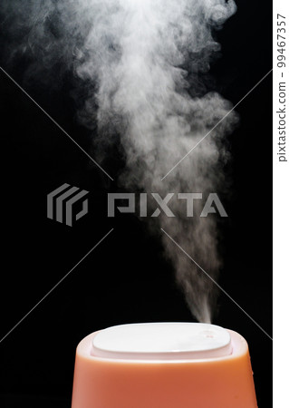 Steam from pink humidifier on a black background. Steam from pink humidifier on a black background. 99467357