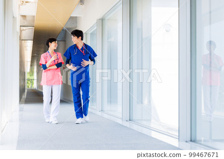Healthcare workers in scrubs walking through a medical facility 99467671
