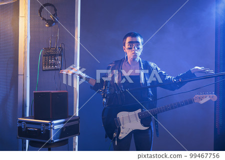 Rock guitarist doing i dont know sign in studio and acting clueless or unsure about decision, being uncertain and doubtful. Heavy metal artist being confused and helpless, unknown answer. Rock guitarist doing i dont know sign in studio and acting clueless or unsure about decision, being uncertain and doubtful. Heavy metal artist being confused and helpless, unknown answer. 99467756