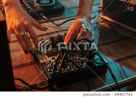 Mixer artist playing key sounds on mixing turntables, using audio dj equipment and stereo instrument to play remix and techno music. Enjoying melody mix at nightclub, stage party in studio. 99467781