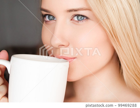 Beautiful blonde woman having a cup of tea in the morning at home. 99469288