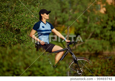 Happy young woman riding a bike in the park Happy young woman riding a bike in the park 99469748