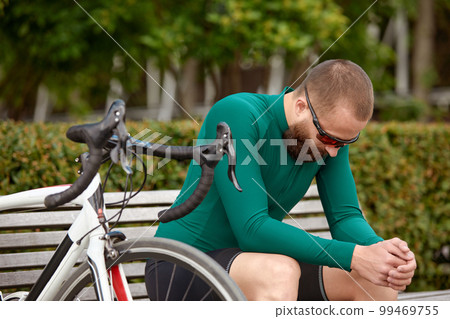 Handsome young man resting after a bike ride Handsome young man resting after a bike ride 99469755