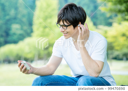 A man with glasses watching a smartphone video in a fresh green park A man with glasses watching a smartphone video in a fresh green park 99470898