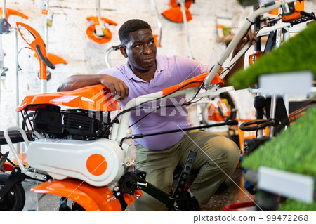 Average customer carefully selects new cultivator at garden tool store Average customer carefully selects new cultivator at garden tool store 99472268