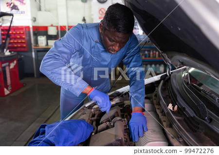 Mechanician changing filter in vehicle in the auto repair shop 99472276