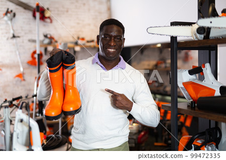 Man chooses rubber boots at garden supply store Man chooses rubber boots at garden supply store 99472335