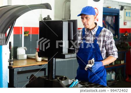 Repairman mechanic at wheel balancing using computer 99472402