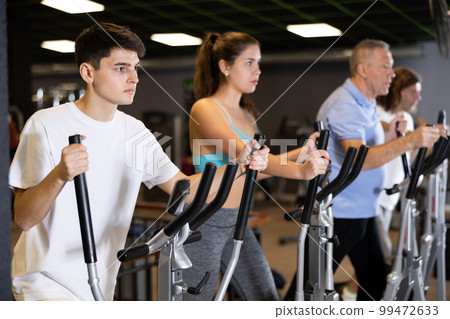 Guy doing cardio training on elliptical machine in gym Guy doing cardio training on elliptical machine in gym 99472633