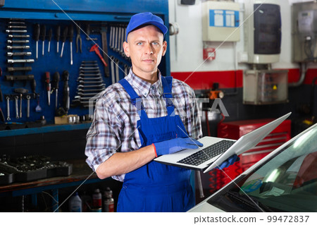 Mechanic man with laptop making car diagnostics at service 99472837