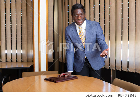 African american entrepreneur inviting to negotiations in meeting room African american entrepreneur inviting to negotiations in meeting room 99472845
