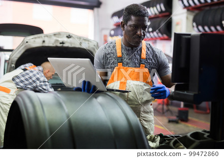African mechanic man using a laptop computer checking car in workshop African mechanic man using a laptop computer checking car in workshop 99472860