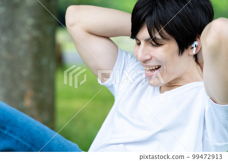 A half man doing muscle training while listening to music in a fresh green park A half man doing muscle training while listening to music in a fresh green park 99472913
