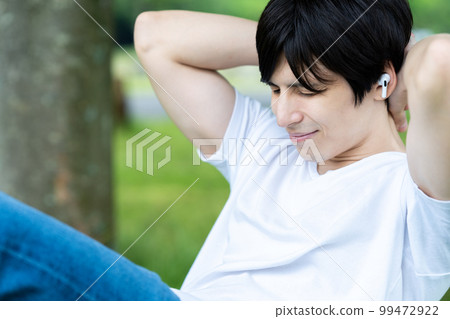 A half man doing muscle training while listening to music in a fresh green park A half man doing muscle training while listening to music in a fresh green park 99472922