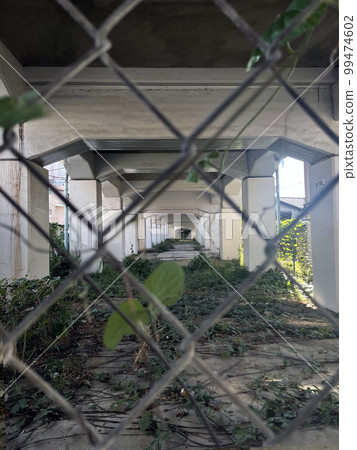 Through the wire mesh under the railway overpass during the day (Focus under the overpass) Through the wire mesh under the railway overpass during the day (Focus under the overpass) 99474602