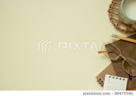 Brown notebook, calendar, eyeglasses, cup of milk, pencil on yellow desk background. flat lay, top view, copy space Brown notebook, calendar, eyeglasses, cup of milk, pencil on yellow desk background. flat lay, top view, copy space 99475580