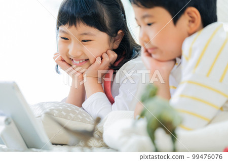 Siblings watching videos in the living room 99476076