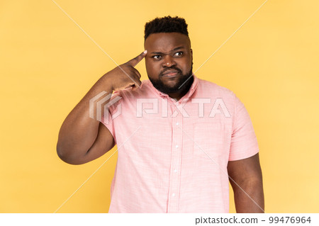 Crazy idea. Portrait of man in pink shirt showing stupid gesture, looking at camera with condemnation and blaming for insane plan, dumb suggestion. Indoor studio shot isolated on yellow background. Crazy idea. Portrait of man in pink shirt showing stupid gesture, looking at camera with condemnation and blaming for insane plan, dumb suggestion. Indoor studio shot isolated on yellow background. 99476964