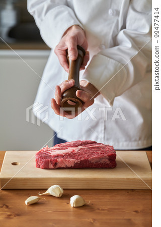 Chef sprinkling spices on thick cut steak Chef sprinkling spices on thick cut steak 99477414