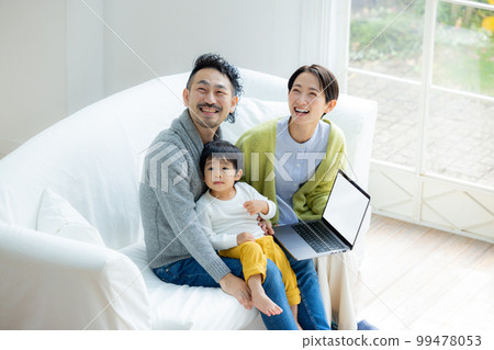A family looking at a computer on the sofa A family looking at a computer on the sofa 99478053