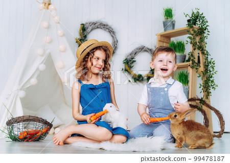 Happy laughing kids feeding rabbits learning to take care of an animal. Happy childhood  99478187