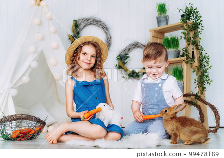 Children feeding rabbits carrots indoor learning to take care of an animals. Happy childhood Children feeding rabbits carrots indoor learning to take care of an animals. Happy childhood 99478189