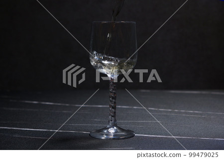 將冰鎮白葡萄酒倒入紅酒杯中 將冰鎮白葡萄酒倒入紅酒杯中 99479025