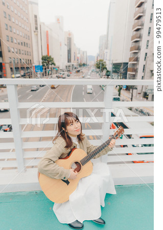 Photo of a woman with a guitar in the city background Photo of a woman with a guitar in the city background 99479513