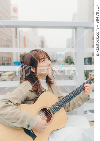 Photo of a woman with a guitar in the city background Photo of a woman with a guitar in the city background 99479517