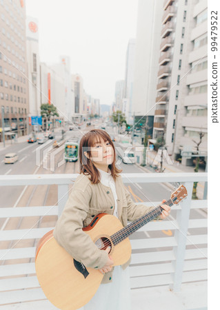Photo of a woman with a guitar in the city background 99479522