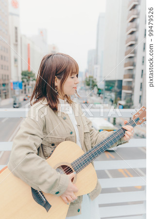 Photo of a woman with a guitar in the city background 99479526