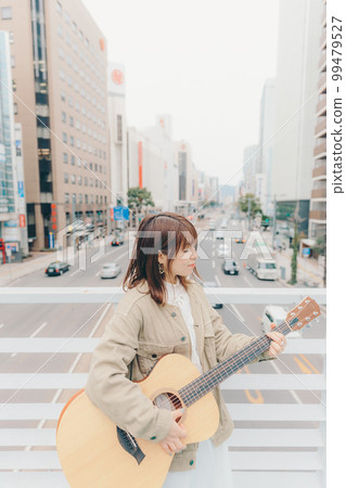 Photo of a woman with a guitar in the city background 99479527