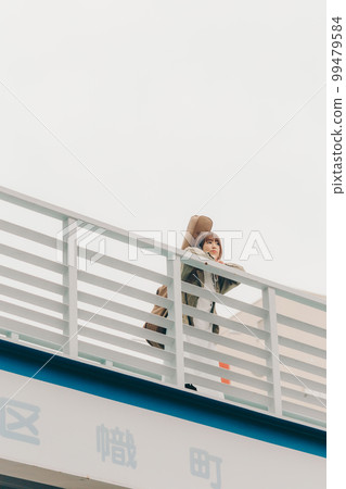 Photo of a woman holding a guitar standing on an overpass 99479584