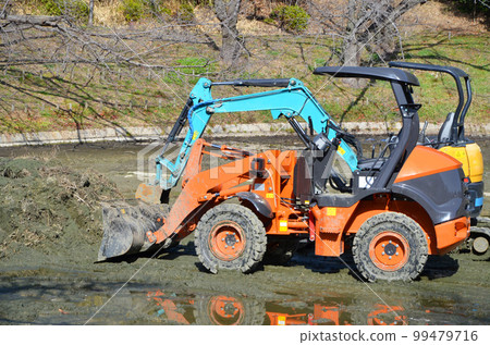 Heavy equipment lowered into a drained pond 99479716