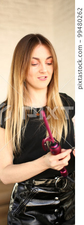 Hairdresser hands curl woman hair with curling irons in salon 99480262