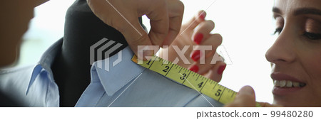 Female hands of tailor with colleague fashion designer will measure clothes on mannequin Female hands of tailor with colleague fashion designer will measure clothes on mannequin 99480280