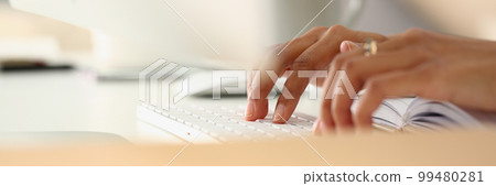 Closeup of female hands typing on keyboard and diary Closeup of female hands typing on keyboard and diary 99480281