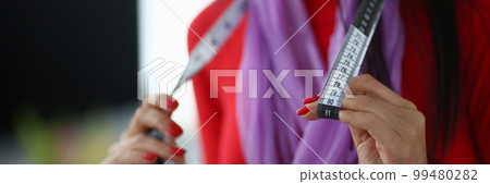 seamstress holds centimeter in hands working closeup 99480282