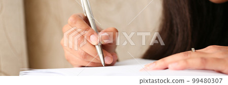 Closeup of hands of black female writer at home writing in magazine Closeup of hands of black female writer at home writing in magazine 99480307