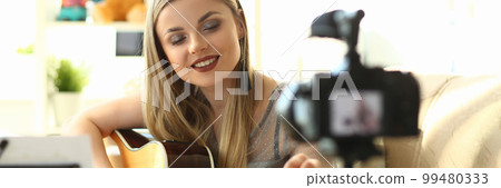 Young woman plays acoustic guitar and records video clips for social networks 99480333