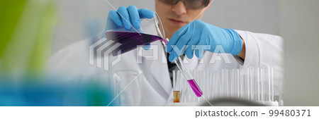 Scientist in protective gloves holding test tube of purple liquid Scientist in protective gloves holding test tube of purple liquid 99480371