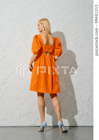 Back view of stylish woman in loose orange dress Back view of stylish woman in loose orange dress 99481313