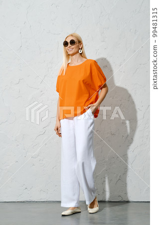 An adult woman walking in a stylish orange and white ensemble 99481315