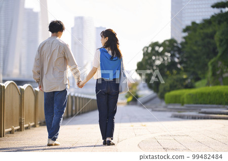 一對年輕夫婦牽著手走路的後視圖 一對年輕夫婦牽著手走路的後視圖 99482484
