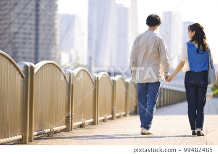 一對年輕夫婦牽著手走路的後視圖 99482485