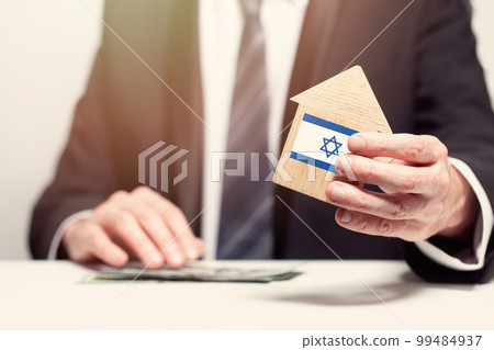 Businessman hand holding wooden home model with Izraeli flag. insurance and property concepts Businessman hand holding wooden home model with Izraeli flag. insurance and property concepts 99484937