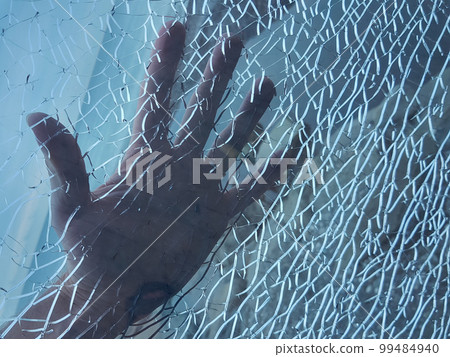 Hand behind blue broken glass with white cracks 99484940