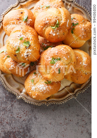 Garlic Herb and Cheese Rolls or Knots bread closeup on the plate on the table. Vertical top view Garlic Herb and Cheese Rolls or Knots bread closeup on the plate on the table. Vertical top view 99486800